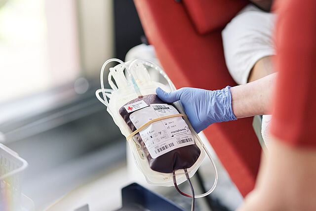 Blutspendebeutel in der Hand eines Blutspendemitarbeiters
