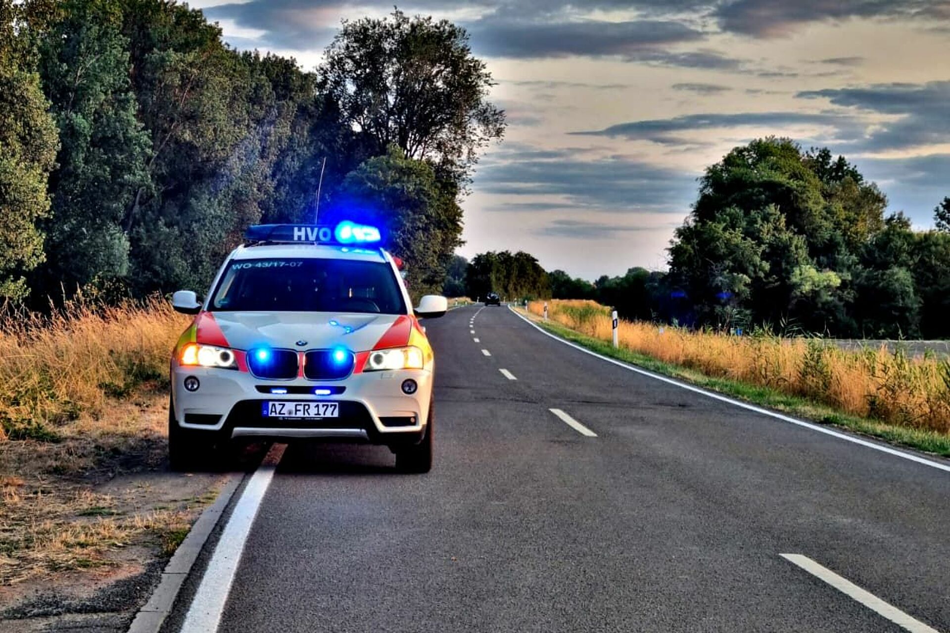 Ein Einsatzfahrzeug des DRK-Ortsverein Altrhein e.V. auf einer Landstraße mit Blaulicht stehend